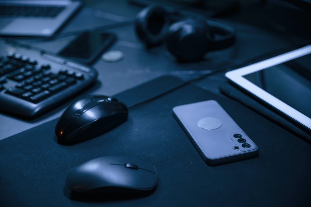 Close up view of table with smartphone, pc mouse, keyboard and headphones