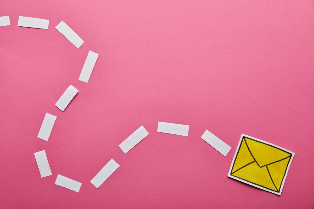 top view of yellow sending delivering email sign on pink background