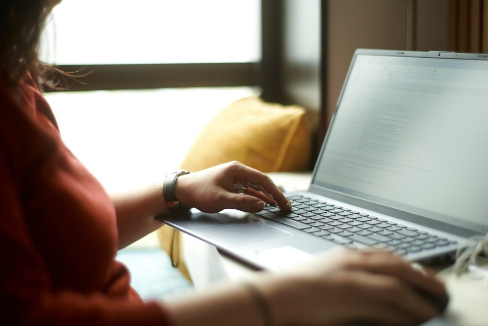 Woman is typing e-mail on laptop. Freelancer answers customer questions from home.